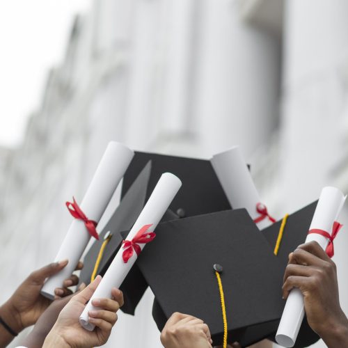 close-up-hands-holding-diplomas-caps